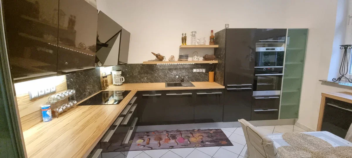 Modern kitchen with black cabinets, wooden countertops, and stainless steel appliances